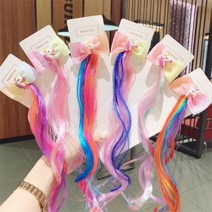 Close-up of five colorful unicorn hair clips with rainbow bows and long synthetic hair
