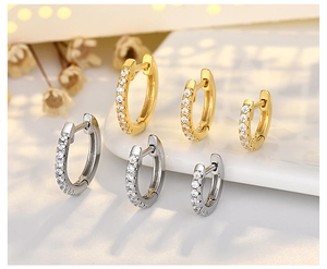 Macro detail of S925 silver rivet hoop earrings with white crystals in gold and silver