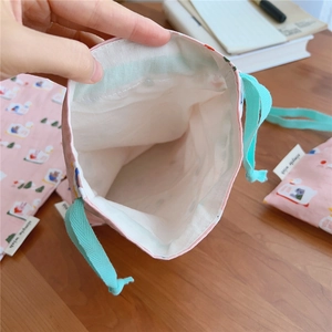 Detail of pink cotton drawstring bag showing white lining and cute duck print patterns