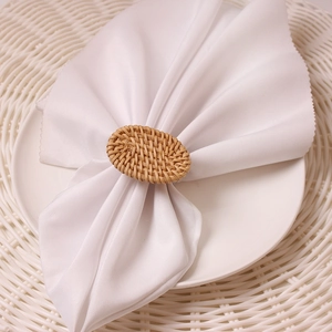 Macro detail of a natural handwoven oval rattan napkin ring on a white linen napkin