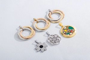 Close-up of assorted stainless steel pendants featuring tree of life and clover designs