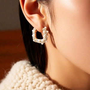 Détail de boucles d'oreilles U dorées avec perles et strass sur un mannequin femme