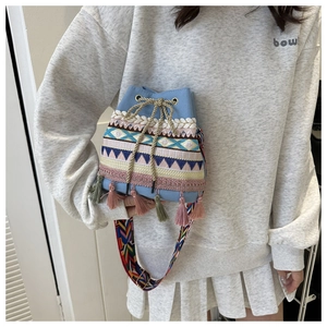 Close-up of ethnic blue bucket bag with colorful embroidery, tassels and wide strap