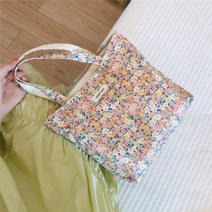 Détail du petit sac cabas en toile avec imprimé floral jaune et rose et étiquette simple