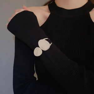 Close-up of a silver irregular double-layered oval cuff bracelet worn on a black sleeve