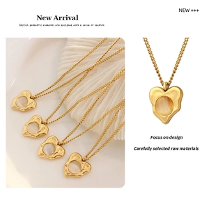 Macro detail of a gold-plated heart pendant necklace with cat-eye stone on a shell