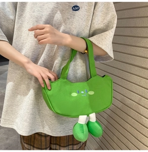 Detail of green canvas tote bag featuring a cute cartoon face and hanging stuffed legs