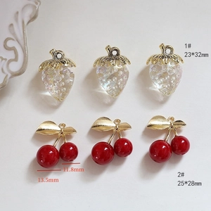 Macro view of translucent faceted strawberry and red cherry charms with gold leaves