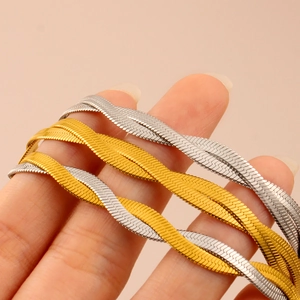 Macro detail of intertwined gold and silver snake bone chains on woman's neck