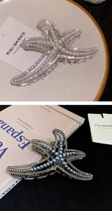 Detail of silver starfish hair claw clip with rhinestones and faux pearls on a book