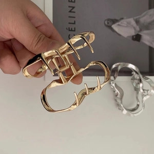Detailed view of silver and gold metal hair claws with irregular wavy cloud designs