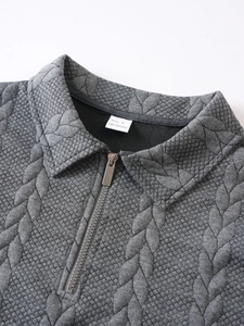 Detail of grey men's quarter-zip pullover showing metallic zipper and geometric texture