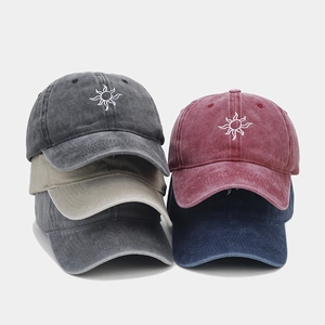 Detailed pile of washed cotton baseball caps showing sun embroidery in various colors