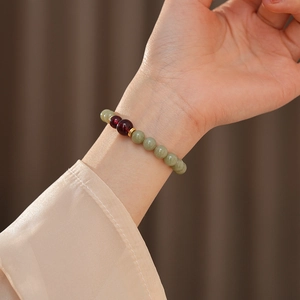 Detail of natural green jade and red agate bead bracelet on a woman wrist