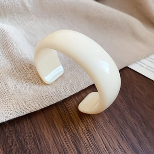 Détail macro d'un bracelet ouvert en acrylique blanc crème avec finition brillante