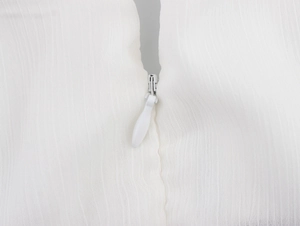 Détail d'une fermeture éclair invisible sur une robe blanche en tissu texturé léger