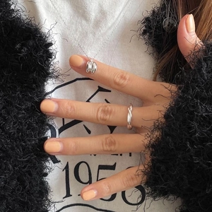 Detail of 925 silver key necklace and twisted rope ring on model with knit cardigan