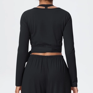 Back view of black long sleeve yoga top with cross-strap detail and wrap tie waist
