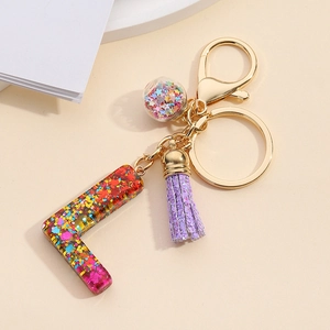 Detail of resin letter L keychain with purple tassel and colorful star sequins