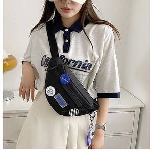 Detail of black nylon crossbody bag with fashion badges and astronaut charm