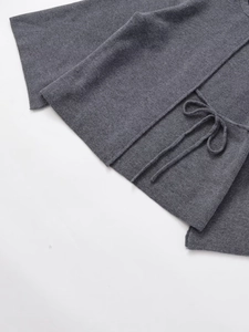 Detail of dark grey knit cardigan featuring side drawstring ties and soft ribbed texture