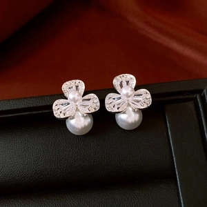 Close-up of elegant flower pearl earrings with zircon inlay on a luxury display stand