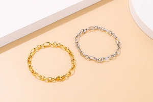 Detail view of gold and silver stainless steel O-link bracelets with lobster clasps