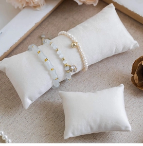 Close-up of pearl and crystal bracelets displayed on white velvet jewelry pillows