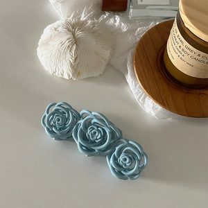 Macro shot of three light blue matte roses on a hair claw clip with floral details