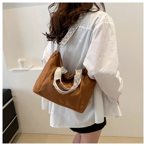 Brown nylon tote bag with patterned wide shoulder strap shown on a model during commute