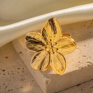 Exaggerated gold flower ring in stainless steel displayed on stone and silk background