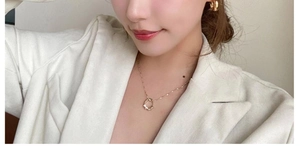 Close-up of elegant gold necklace and earrings set worn by a model in a white blazer