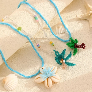 Close-up of summer ocean jewelry set with beads, shells, and palm tree charms on sand