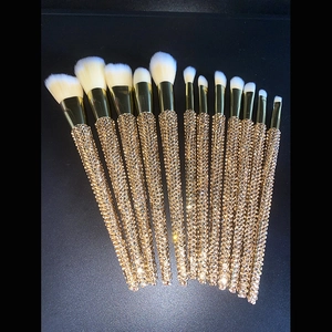 Detail of 12-piece gold rhinestone makeup brushes with soft white synthetic bristles