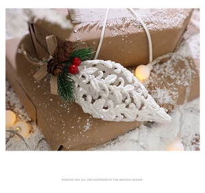 Detailed view of a white glitter Christmas teardrop ornament with pine cones and berries
