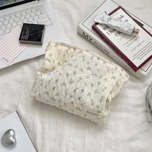 Trousse de toilette florale en toile avec fleurs jaunes et étiquette Sosakka sur draps