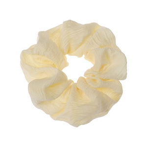 Close-up of pleated fabric scrunchie in pale yellow and cream white for bun hairstyles