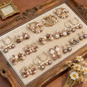 Détail macro de boucles d'oreilles perles vintage et finition dorée sur plateau velours