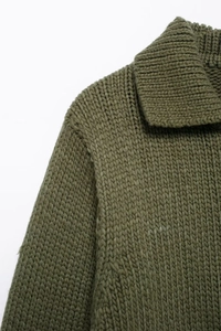 Dettaglio maglione in maglia verde con colletto a rever e trama delle spalle