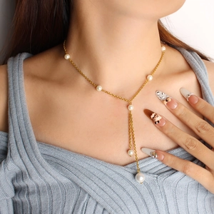 Close-up of elegant gold Y-shaped fringe necklace with white pearls on a model