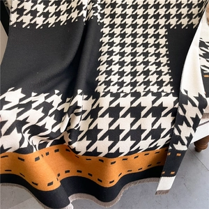 Close-up of black and white houndstooth scarf texture with brown trim and fringes