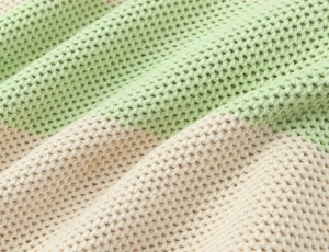 Macro detail of light green and cream waffle knit texture with honeycomb stitching