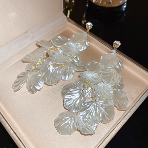 Macro shot of white shell flower earrings with gold tassel and sparkling rhinestone