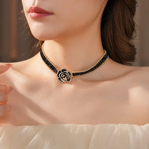 Close-up of elegant black flower choker necklace with gold edges on a model's neck