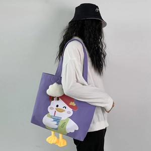 Detail of purple canvas tote bag with 3D duck feet and cloud charm on a model's shoulder