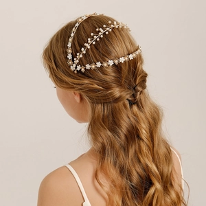 Golden bridal hair vine with white flowers and pearls on elegant wedding hairstyle