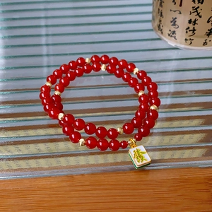 Detail of red agate bead double-layer bracelet with a gold fortune mahjong charm