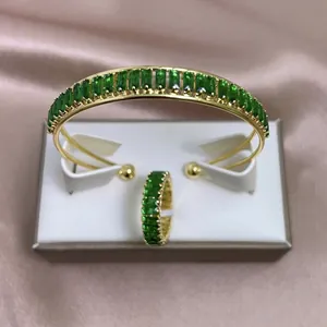 Conjunto de joyas de lujo con pulsera y anillo dorados y piedras preciosas verdes brillantes