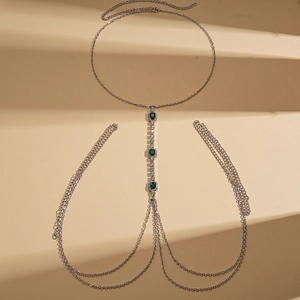 Detailed macro view of silver body chain with green square stone and rhinestone tassels