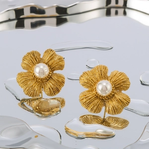 Vintage 18K gold plated clover earrings with pearls on reflective water surface